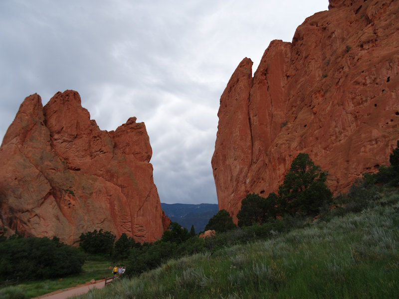 a far-away group of people walking through a pair of massive red rock formations