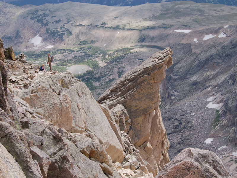two adventerous hikers stand atop a cliffside overlooking a valley